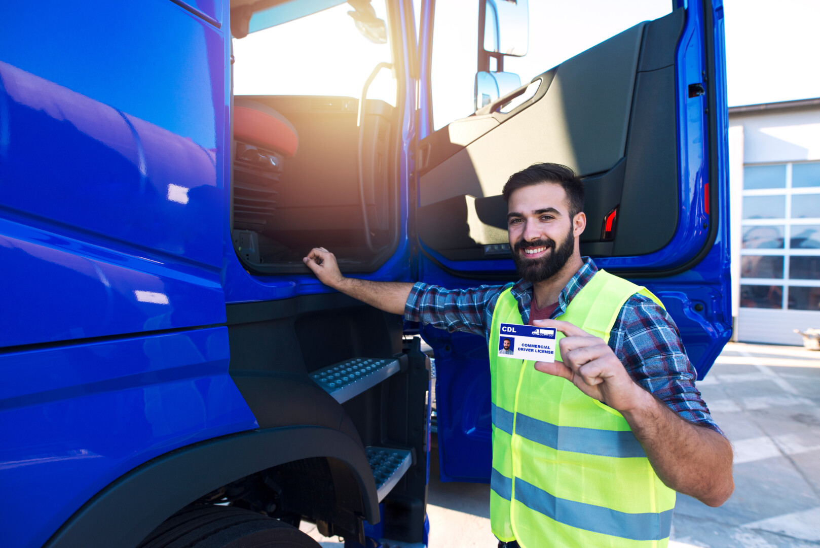 CDL driver holding license outside truck.