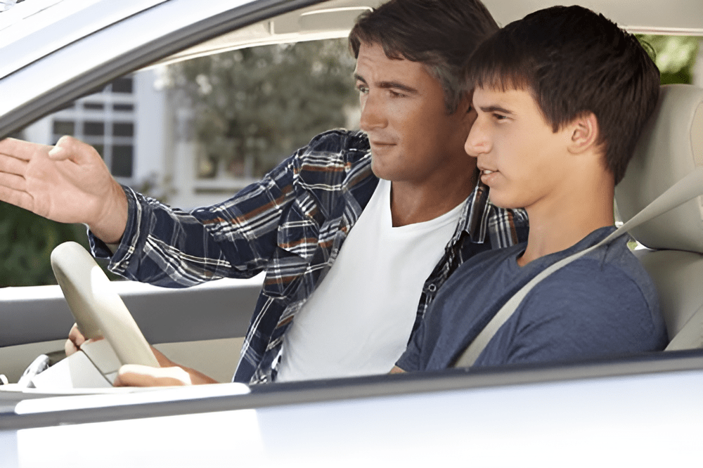 Father instructing son in driver’s seat on Texas Parent Taught Driver Education principles for behind-the-wheel training.