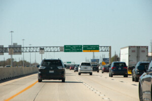 Car driving on a wide Texas highway with open fields on either side.