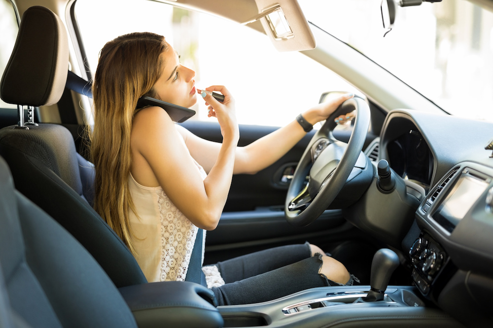 woman distracted driving while putting on makeup.