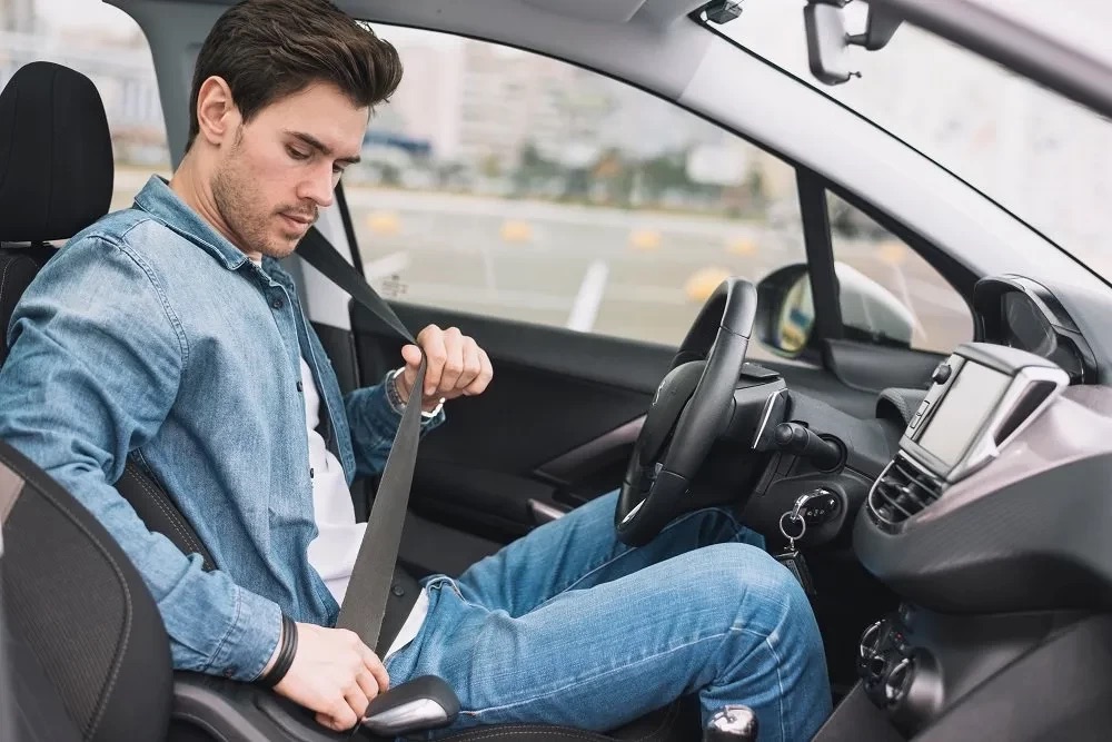 Driver buckling up their seat belt before driving.