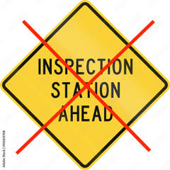 Yellow road sign with "Inspection Station Ahead" crossed out, symbolizing the end of vehicle inspections in Texas.